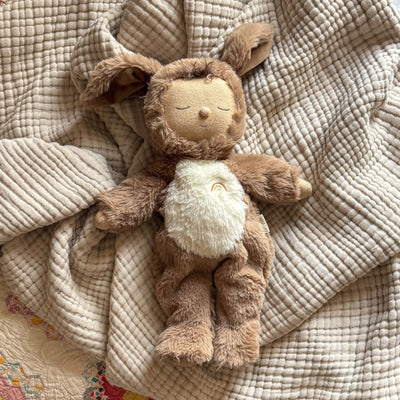 Cozy Dinkums Dog Digby plush dog doll with floppy ears, soft brown fur, cream belly, and rainbow embroidery resting on a textured quilt blanket