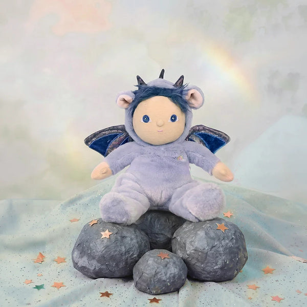 Stuffed toy in a purple outfit with wings and horns on rocks with a starry background