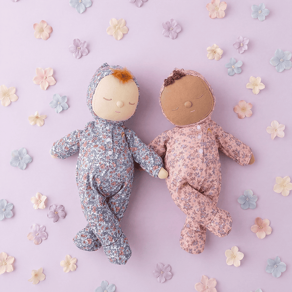 Two dolls in floral outfits on a light purple background with flowers.