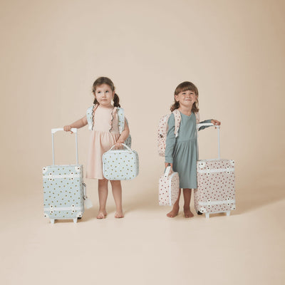 Two children with wheeled suitcases, matching carry bags, and backpacks in pastel blue and pink patterns from Olli Ella Kids.