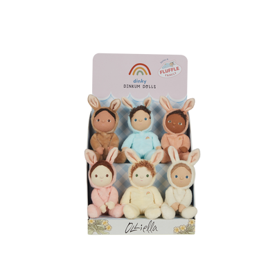 Display box holding six Dinky Dinkums Fluffle Family plush dolls with bunny ears in soft pastel outfits, arranged in two rows for Easter gifting