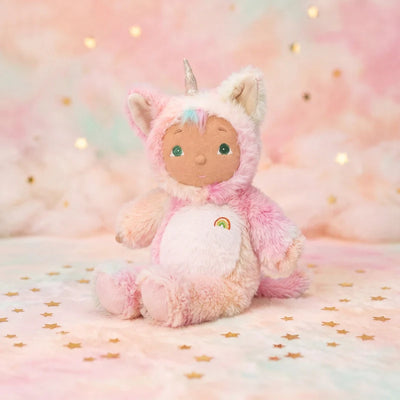 Pink plush kittycorn doll with a soft white belly, rainbow detail, horn, and cat ears, seated on a star patterned backdrop from Cozy Day Dinkums