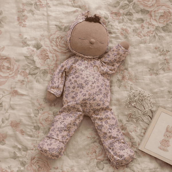 Stuffed doll in floral outfit on a floral-patterned surface