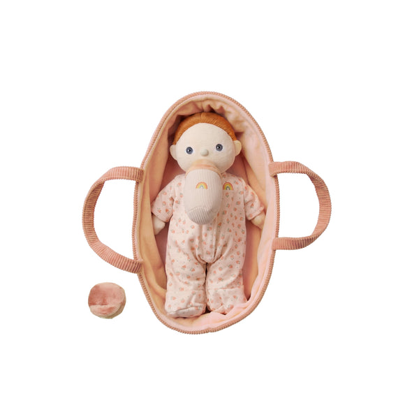 Small Binky Dinky doll in a peach patterned outfit resting in a soft peach bassinet, with a matching pacifier beside it from Dinkum Dolls by Olli Ella