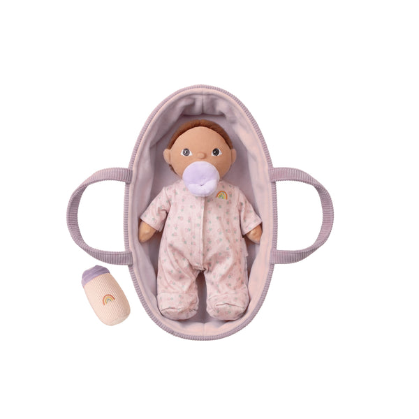 Baby doll in a crib with a pacifier on a white background