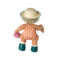 A doll viewed from the back, wearing a straw hat with a turquoise rim, an orange and white striped swimsuit, teal shoes, and holding a pink heart-shaped accessory.