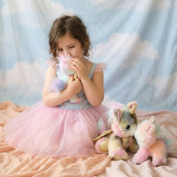 Young girl in a pink dress holding a plush toy with a cloud-patterned backdrop