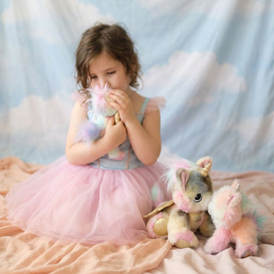 Young girl in a pink dress holding a plush toy with a cloud-patterned backdrop