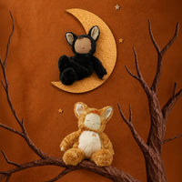 Black Cozy Dinkum cat plush doll resting on a crescent moon above a golden cat plush perched on a branch, styled by Dinkum Dolls by Olli Ella