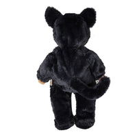 Back view of Cozy Dinkum Cat Nox, a soft black plush cat doll with rounded ears, furry body, short legs and a curved tail.