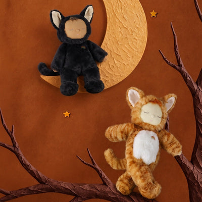 Black Cozy Dinkum Cat plush toy perched on a crescent moon beside an orange tabby plush, styled by Dinkum Dolls by Olli Ella in a warm woodland scene