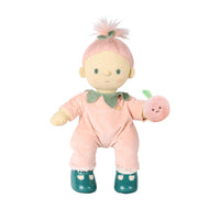 A plush doll with pale skin, green eyes, and pink hair styled like a ponytail with a small green leaf accent. The doll wears a pink outfit with a green collar and holds a small pink apple toy against a plain white background.