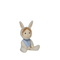 Dinky Dinkums Biffle Bunny plush doll with soft cream fur, tan bunny ears and hair, and a blue outfit, seated with legs outstretched on a green background