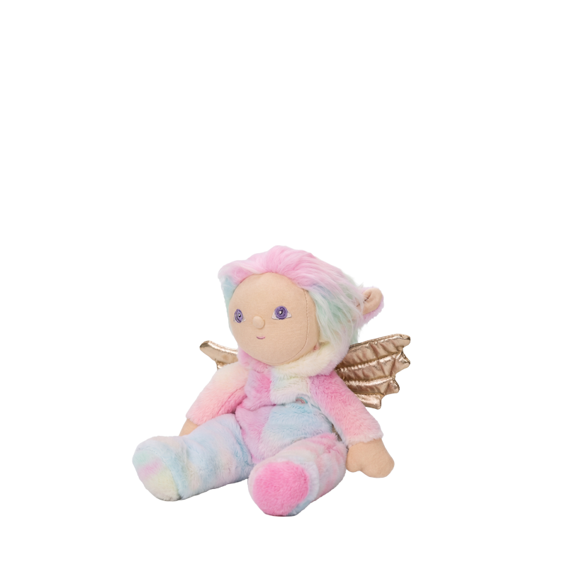 Dinky Dinkums Yara Unicorn plush doll with pastel rainbow hair, pink and blue outfit, and shimmering gold wings, seated against a dark background