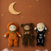 Dinkum Dolls by Olli Ella Jules Jack-o-Lantern doll in an orange pumpkin costume beside bear and skeleton dolls on a moonlit Halloween backdrop