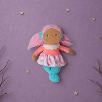 Dinky Dinkum Lottie Lollipop doll with pink hair, coral top, candy swirl skirt, and turquoise tights lying on a purple background with star accents
