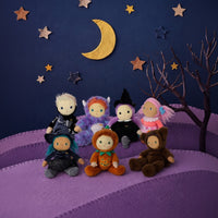 Miles Monster plush doll in an orange pumpkin outfit sits with costumed friends on purple steps beneath a crescent moon, stars, and a spooky tree by Dinkum Dolls by Olli Ella