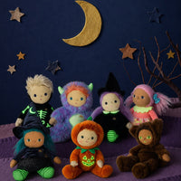 Scully Skeleton doll from Dinkum Dolls by Olli Ella sits among colorful Halloween dolls beneath a crescent moon and stars, wearing a black outfit with glowing green bones