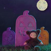 Dinky Dinkum Wesley Werewolf plush doll sitting in grass before colorful pumpkin tombstones under a full moon, from Dinkum Dolls by Olli Ella
