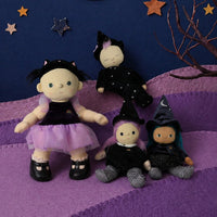 Dinky Dinkum Winnie Witch doll with green hair and a pointed hat sits beside three costumed dolls on a purple quilted blanket beneath star decorations.