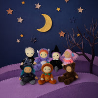 Green haired Winnie Witch doll in a black witch costume with striped leggings, seated among Halloween dolls beneath a crescent moon and stars. Dinkum Dolls by Olli Ella
