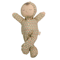Soft baby doll with sleepy embroidered closed eyes, a smiling mouth and a tuft of brown hair, wearing a cream footed sleepsuit and matching bonnet printed with small red and green sprigs, with arms raised and legs crossed.