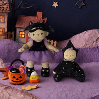 Sleeping black witch doll in a starry outfit beside a larger witch doll, pumpkin treat bucket, candy corn, and Halloween cottage decorations from Dinkum Dolls by Olli Ella