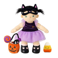 Dream Dinkum doll dressed in a sparkly purple cat costume with black shoes, a pumpkin trick or treat basket and lollipop beside a candy corn plush.