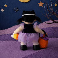 Back view of Dream Dinkum Doll Mabel Moon in a purple witch costume and black hat holding a pumpkin basket for Halloween trick or treating