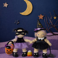 Dinkum Dolls by Olli Ella Dream Dinkum dolls dressed as a witch and cat for Halloween, holding hands beside a pumpkin basket under a crescent moon and stars