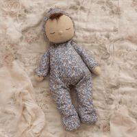 Baby doll in floral outfit lying on a floral blanket