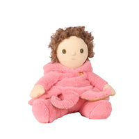 A plush doll with curly brown hair wearing a soft pink hooded robe, seated against a plain white background.