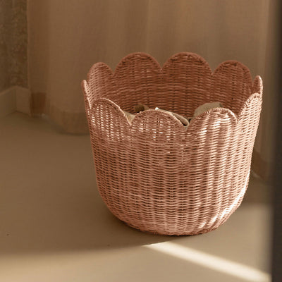 Seashell pink rattan tulip basket with scalloped edges, photographed in warm sunlight, from Olli Ella Nursery for stylish home storage and decor
