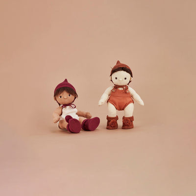 Two Dinkum Dolls posed together, with one seated and one standing in an umber knit bonnet and cosy booties with fluffy pom poms.