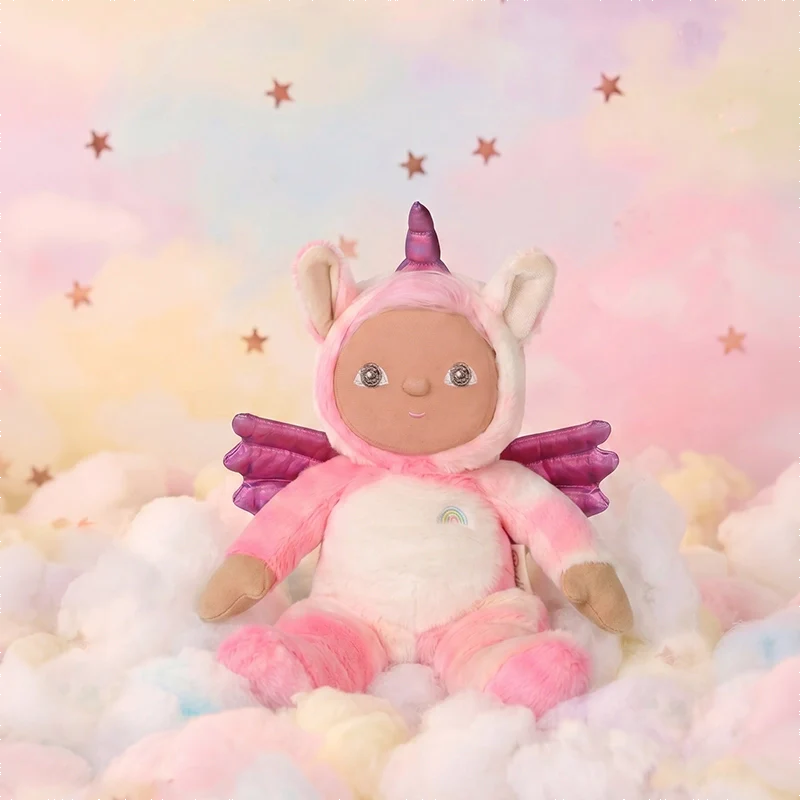 Pink unicorn plush doll with wings and rainbow detail sitting among pastel clouds, Dinky Dinkums Yuna Unicorn soft toy against a starry sky
