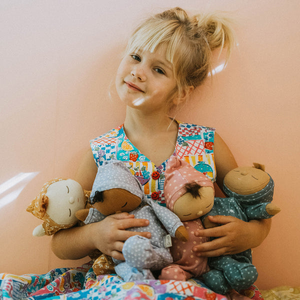 Dozy Dinkum doll with tan velvety onsie outfit. Perfectly weighted doll for calm. Plush doll with red hair, perfect for cuddling and interactive doll play.