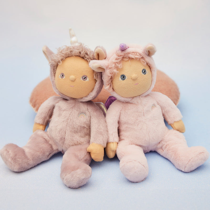 Two pastel pink Dinky Dinkums unicorn dolls sitting side by side, with soft plush bodies, curly hair, sweet embroidered faces, and whimsical horned hoods.