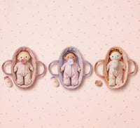 Three baby dolls in miniature cribs on a pink polka dot background