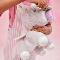 Lilac Dinkum Unicorn Glimmer plush toy with a purple horn, white hooves and soft wings, lovingly held by a child in pink striped clothing