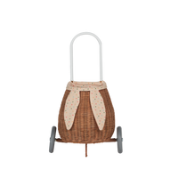 Rattan bunny luggy basket with floppy fabric ears, speckled Gumdrop lining, tall handle, and wheels, shown from the front by Olli Ella Kids Rattan