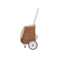 Side view of an Olli Ella rattan bunny luggy with a speckled Gumdrop lining, floppy bunny ear, white pull handle, wheel, and fluffy tail
