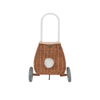 Rattan bunny luggy basket with white handle, speckled lining, fluffy white pom pom detail, and two wheels by Olli Ella Kids Rattan