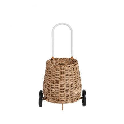 Natural rattan wheeled basket with a white loop handle, designed for toddlers to store and carry treasured belongings from room to room