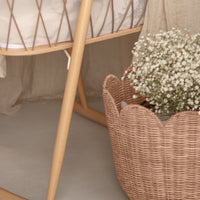Seashell pink rattan tulip basket filled with delicate white flowers in a soft neutral nursery setting by Olli Ella Nursery