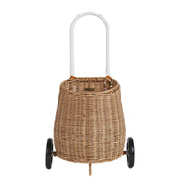Natural rattan wheeled basket with a tall white handle, black wheels, and woven construction for toddlers to store and carry belongings