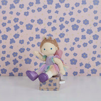 Dinkum Dolls fairy outfit shown on a doll, featuring sparkly wings, a tulle tutu, matching headband and pastel bodysuit on a floral box.